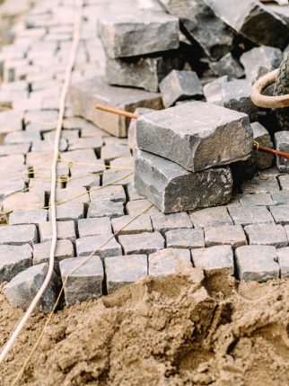 Construction site - details of pavement road building with cobblestone blocks, wheelbarrow and level tools