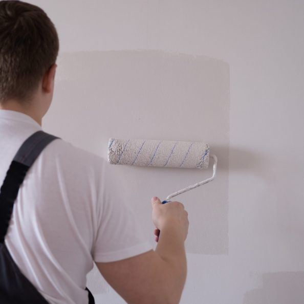 Home renovation works and tips. Male painting a wall with white color.